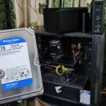 Mô tả người dùng cầm ổ cứng HDD trước PC và hai thiết bị NAS TerraMaster.