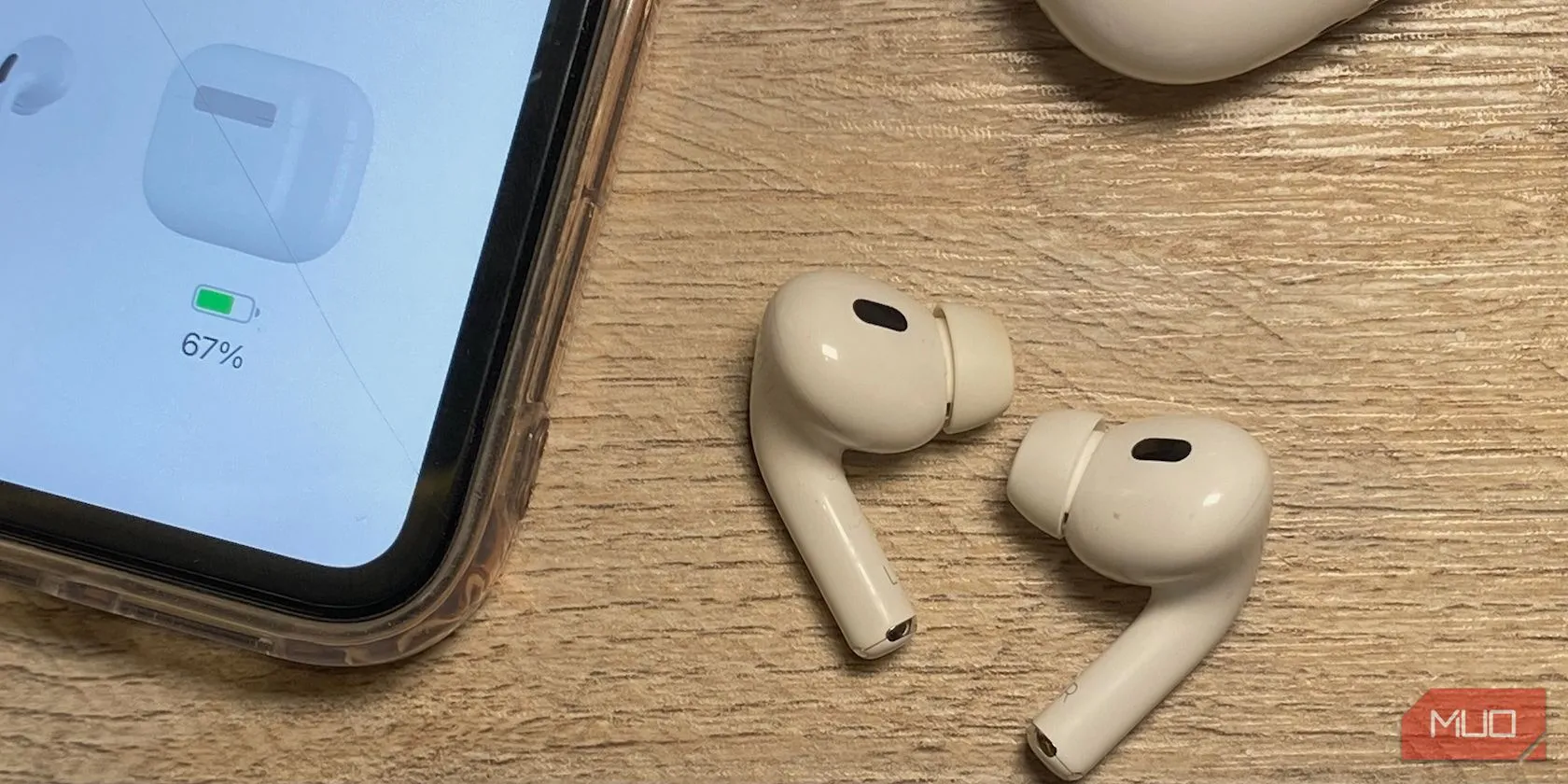 Các thế hệ AirPods khác nhau trên bàn gỗ cạnh iPhone