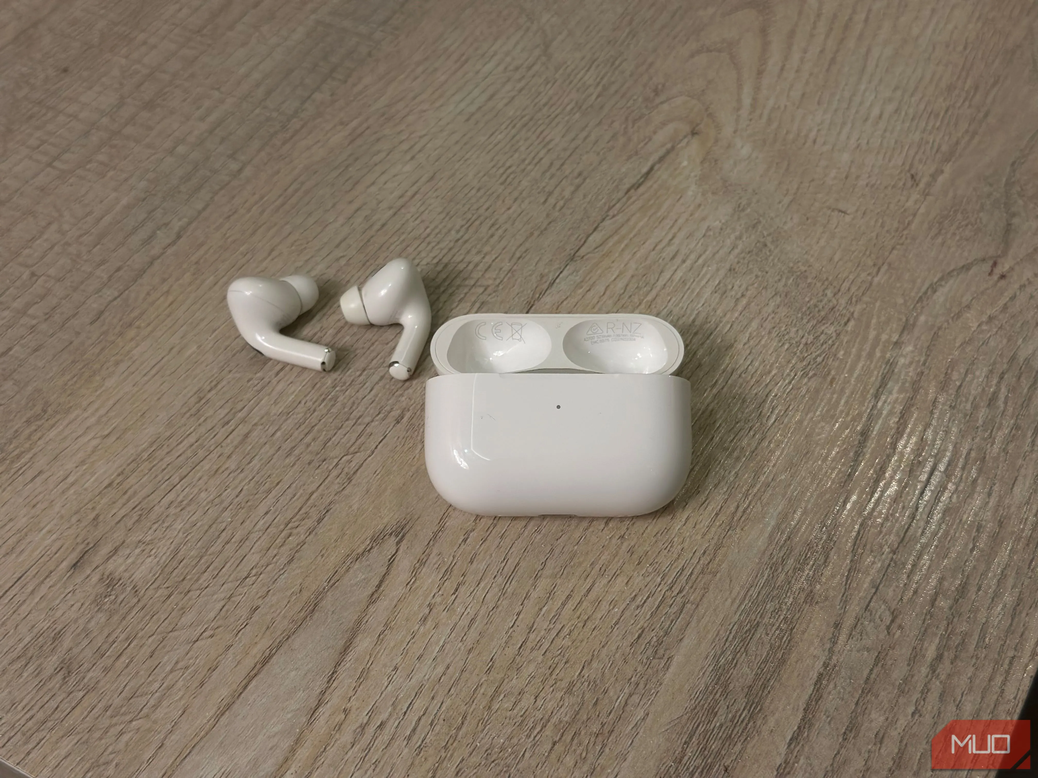 Hộp sạc AirPods và tai nghe trên bàn, hiển thị số model và serial