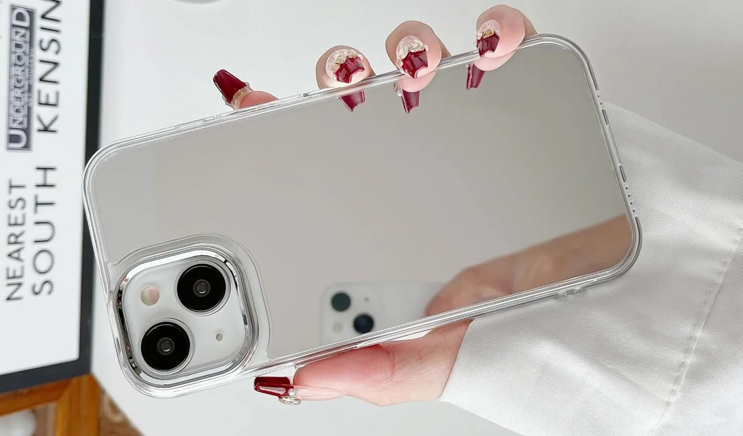 Bàn tay đang cầm iPhone với ốp lưng có mặt phản chiếu giống gương
