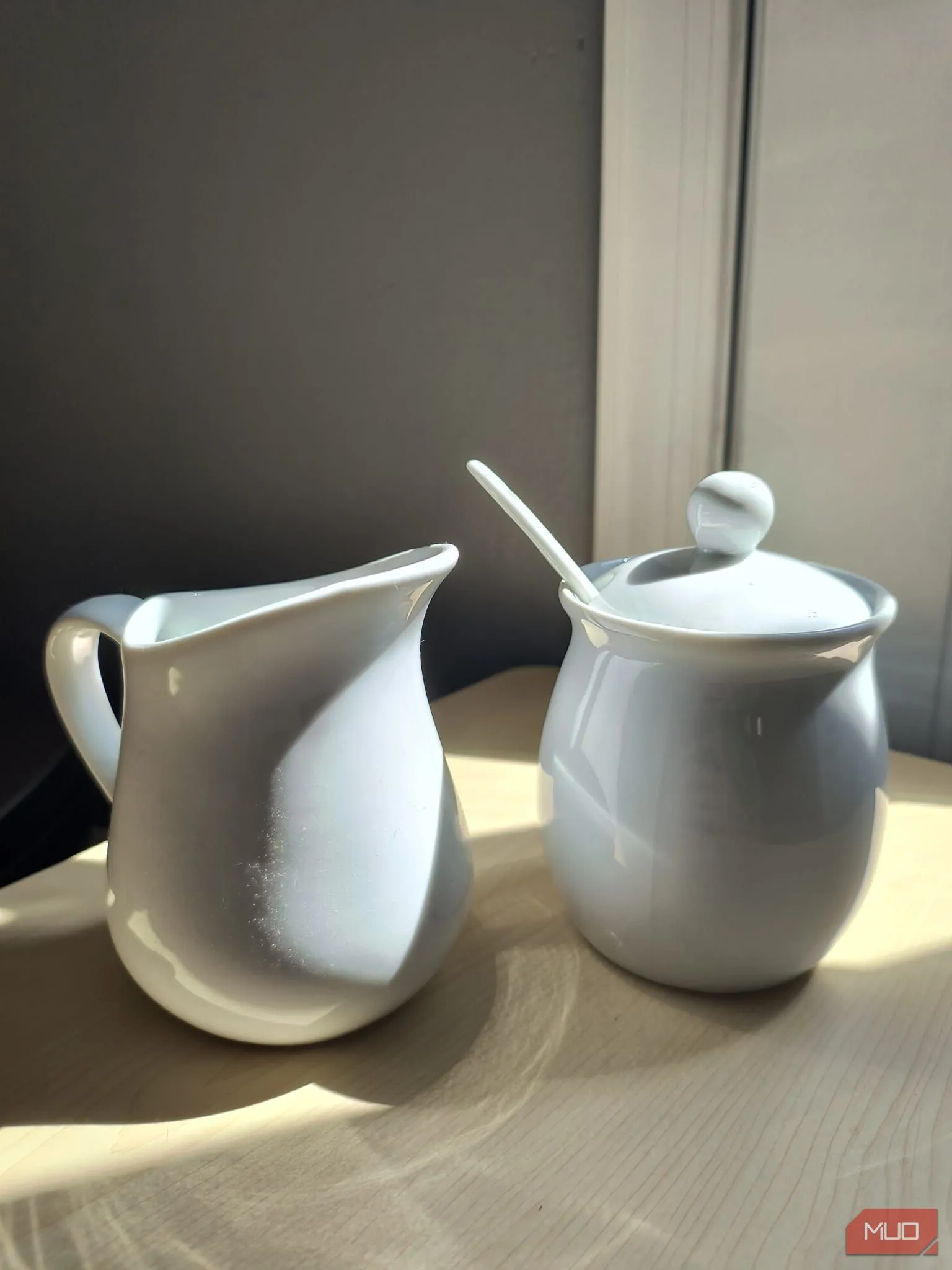 Bộ đồ sứ trắng đựng đường và kem đặt dưới ánh nắng trực tiếp, bật HDR