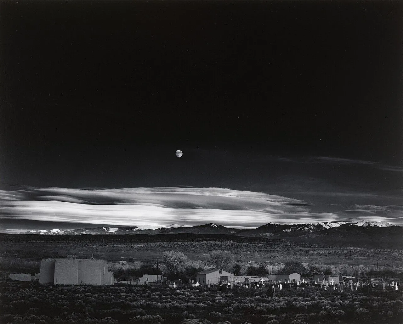 Bức ảnh đen trắng nổi tiếng &quot;Moonrise, Hernandez, New Mexico&quot; của Ansel Adams, chụp cảnh mặt trăng trên thị trấn sa mạc với độ tương phản cao.