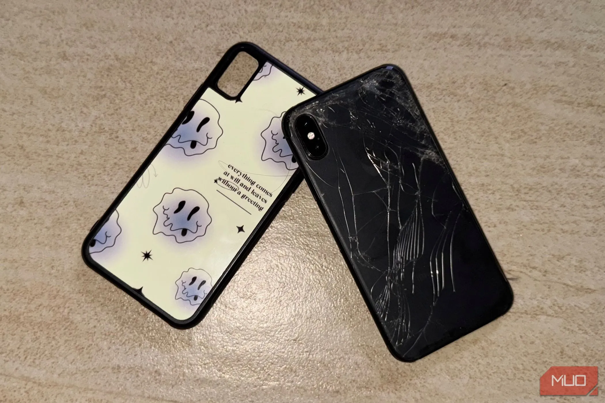Chiếc iPhone X với mặt lưng kính bị nứt nằm trên sàn nhà kèm ốp lưng