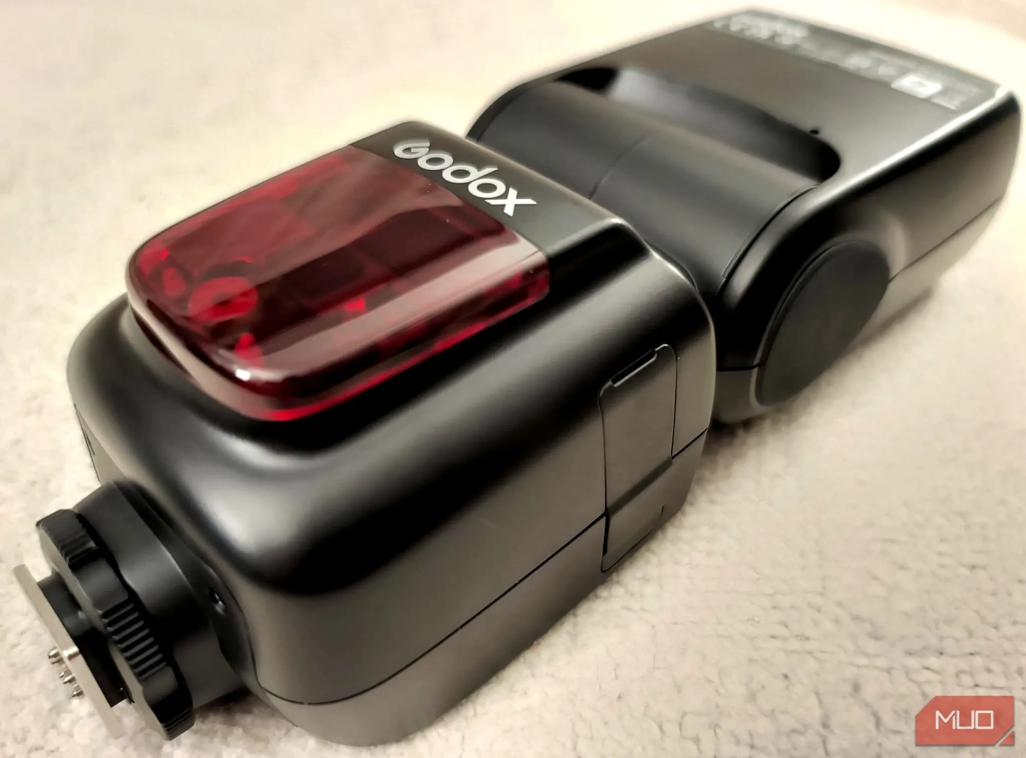 Đèn flash rời Godox V860II-C nằm trên tấm chăn màu be, minh họa thiết kế chắc chắn và bền bỉ của sản phẩm.