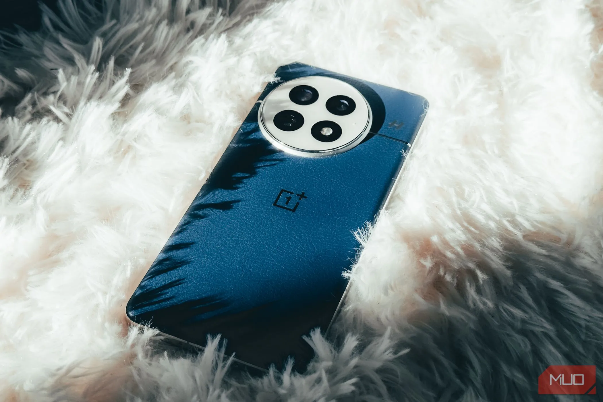 Điện thoại OnePlus 13 màu Midnight Ocean đặt trên thảm lông trắng, làm nổi bật thiết kế cao cấp và chất liệu da vegan