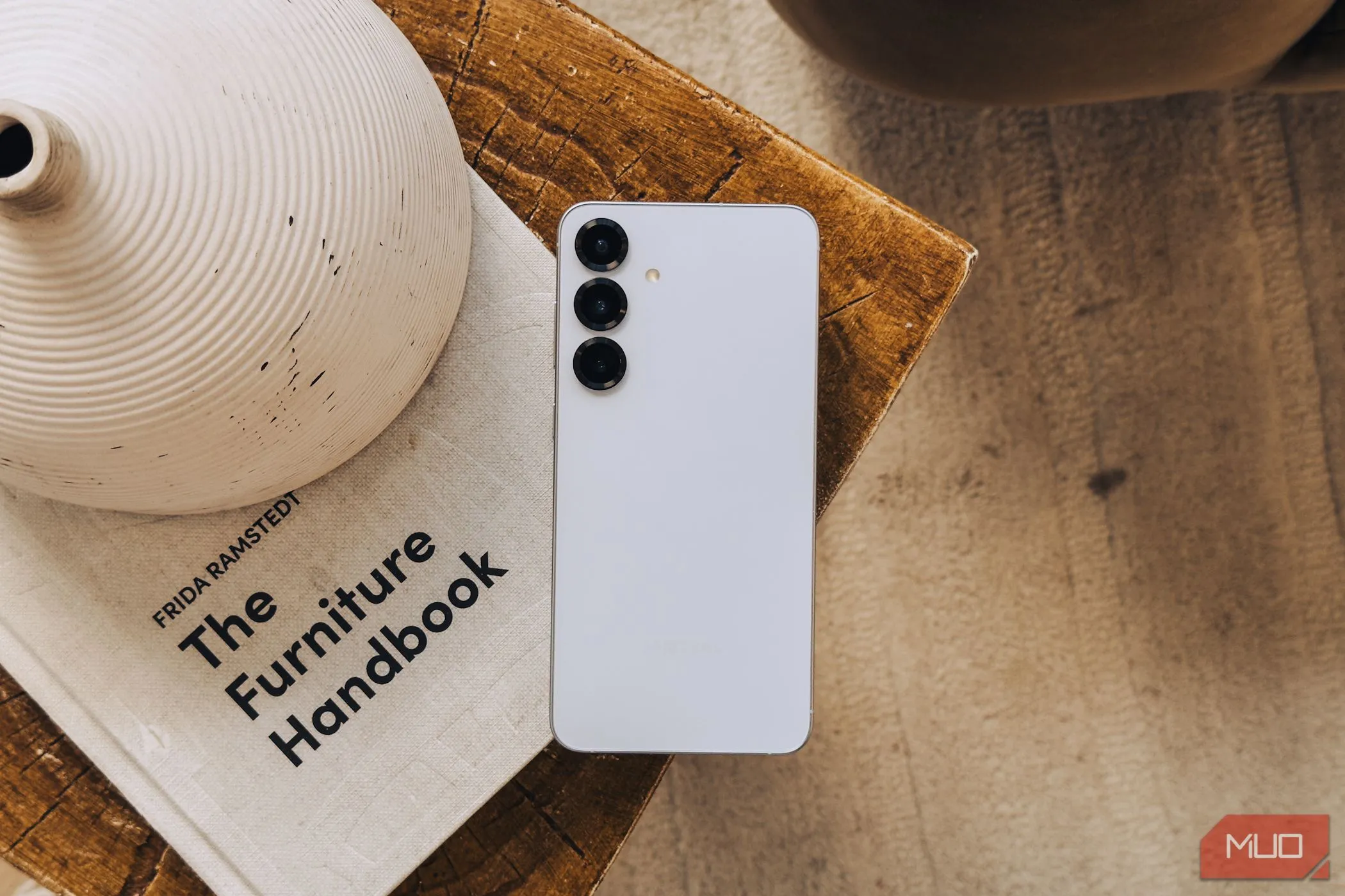 Điện thoại Samsung Galaxy S25 màu bạc đặt trên cuốn sách trắng, thể hiện cụm camera không có nhiều thay đổi