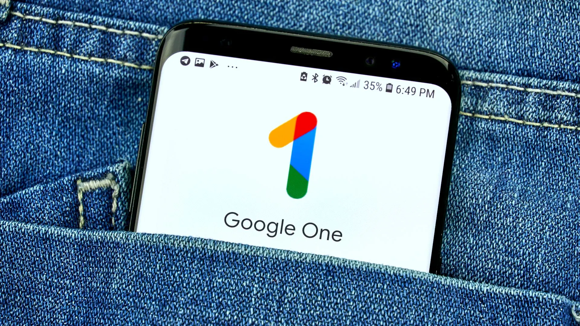 Màn hình ứng dụng Google One trên điện thoại thông minh đặt trong túi quần jean, minh họa tính di động của lưu trữ đám mây.