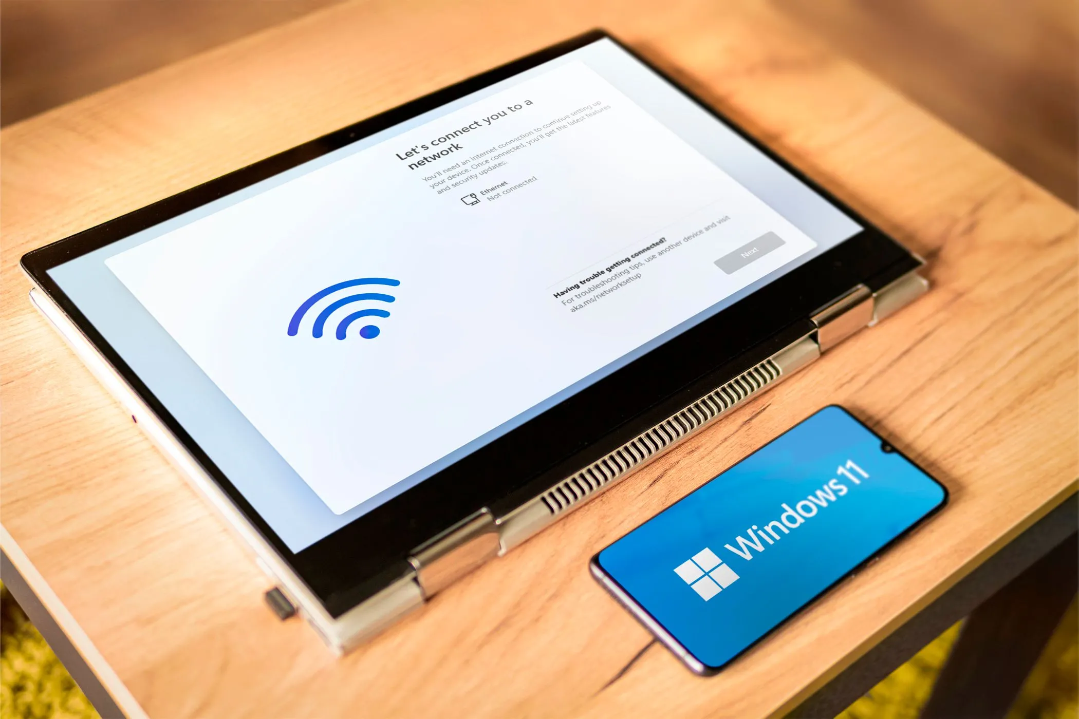 Máy tính xách tay và điện thoại Android hiển thị logo Windows 11, minh họa việc sử dụng điện thoại làm màn hình phụ cho PC hoặc laptop.