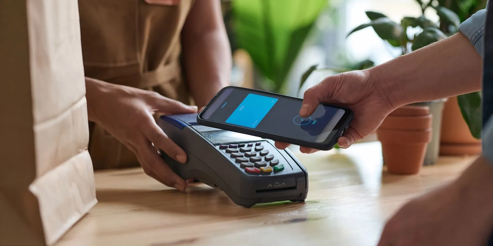 Người đàn ông sử dụng điện thoại thông minh để thanh toán không chạm tại cửa hàng tạp hóa