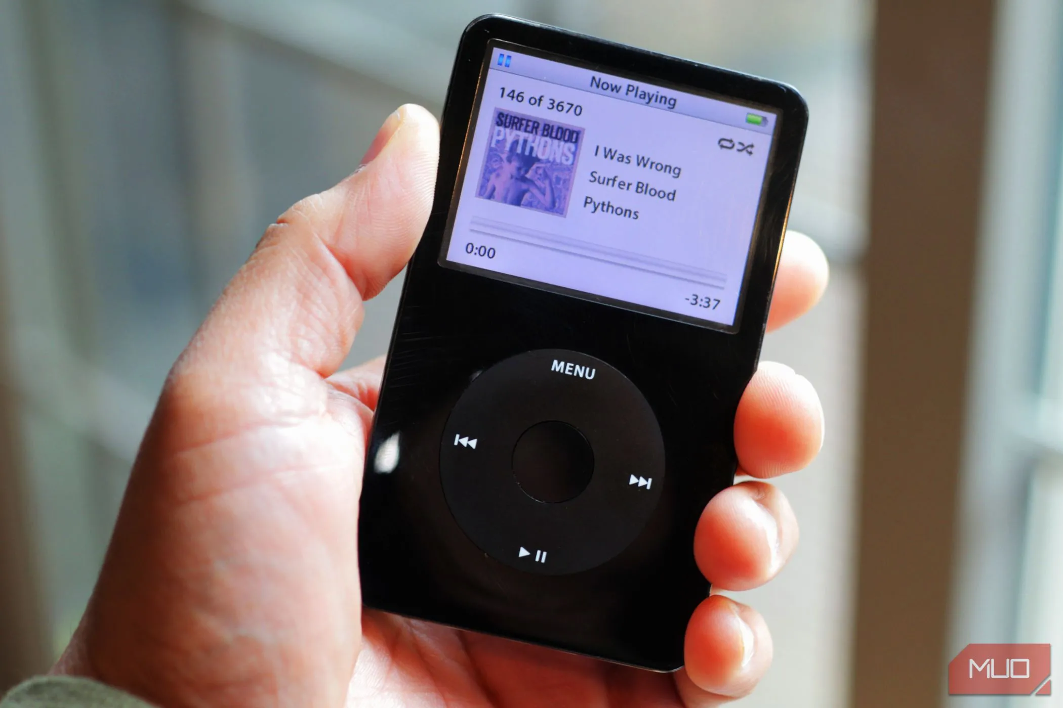 Người dùng cầm chiếc iPod Classic màu đen gần cửa sổ