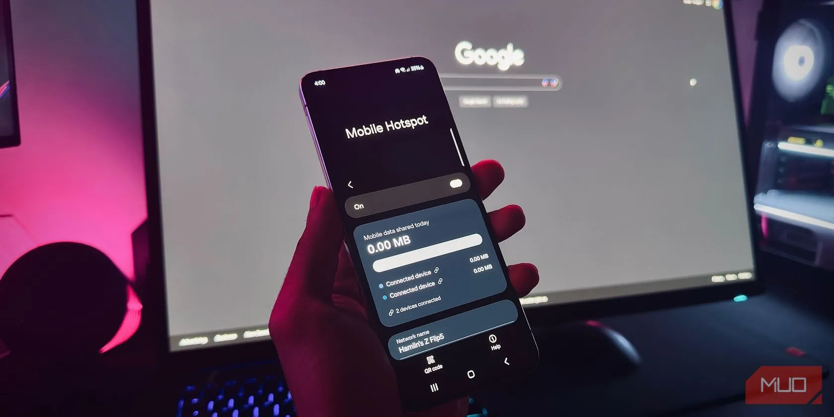 Người dùng cầm điện thoại Android đang bật tính năng Mobile Hotspot trước màn hình máy tính, minh họa việc tối ưu vị trí để cải thiện tốc độ kết nối.