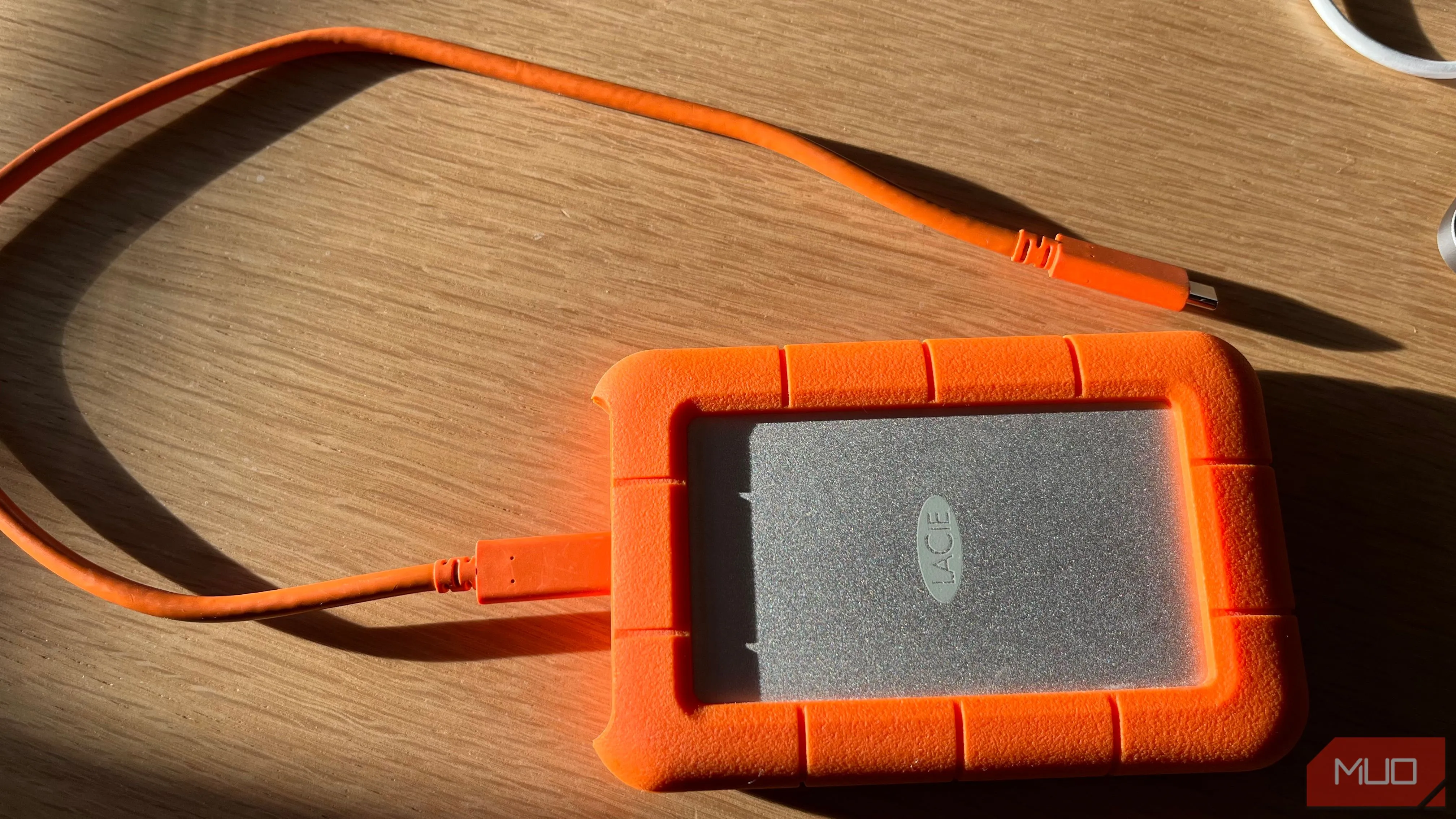 Ổ cứng ngoài LaCie Rugged màu cam đặt trên bề mặt gỗ