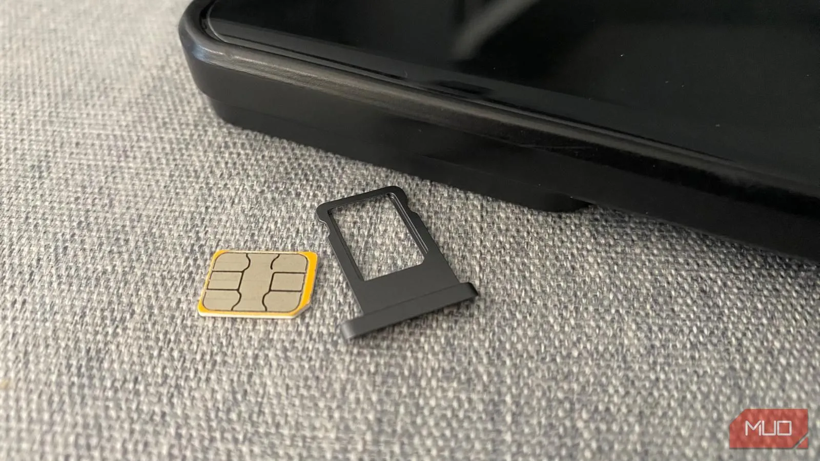 Thẻ SIM vật lý và khay đựng đặt cạnh điện thoại di động trên mặt bàn, đại diện cho SIM truyền thống