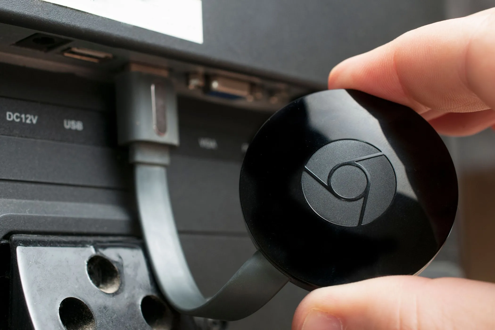 Thiết bị Chromecast đang cắm vào TV, sẵn sàng chiếu nội dung từ điện thoại