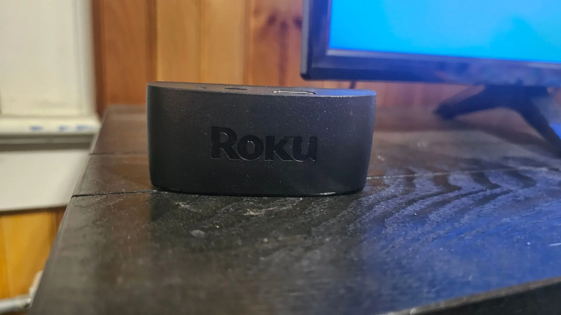Thiết bị phát trực tuyến Roku đặt trên kệ TV cạnh màn hình